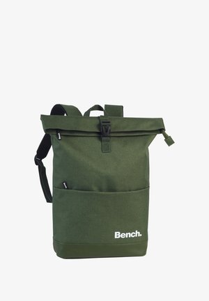 Sac à dos vert à rabat fabriqué en tissu durable avec des bretelles ajustables. Comprend une poche avant et un imprimé de logo blanc en bas.