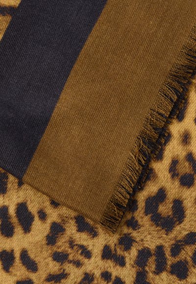 Καρό μάλλινο κασκόλ με φουντίτσες, με φαρδιές σκούρες καφέ και καμηλό ρίγες, τοποθετημένο πάνω σε ύφασμα με λεοπάρ σχέδιο σε ταμπά και μαύρο.