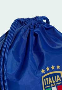 Modrý batoh na sťahovanie s hladkou nylonovou textúrou. Obsahuje žltý a zelený erb s hviezdami, ktorý symbolizuje talianske futbalové dedičstvo.