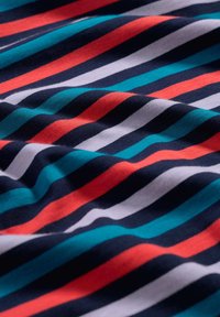 Gestreifter Stoff mit marineblauen, roten, türkisfarbenen und weißen Linien. Das Material wirkt weich mit einer glatten Textur und hat einen fließenden Fall.