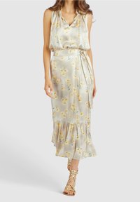 Robe en soie à motif floral jaune sur fond clair, avec un décolleté en V, des détails à cordon et un ourlet à volants.