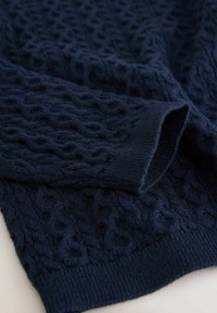 Marineblå strikket sweater med et tekstureret kabelmønster, der har ribbet kant og ærmer. Blødt, tykt materiale giver varme.