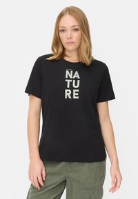 Sort kortærmet T-shirt lavet af bomuld, med teksten "Empowered by Nature" i lys grøn farve tværs over fronten. Enkel, afslappet pasform.