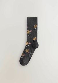 Chaussettes grises avec un motif de personnages de dessins animés ayant des têtes jaunes, des nœuds rouges et des chaussures blanches. Poignet côtelé. Texte : "BUTTER TOGETHER."