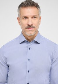 Camicia a righe azzurro chiaro con colletto button-down, maniche lunghe e bottoni blu scuro, caratterizzata da una superficie liscia e una vestibilità su misura.