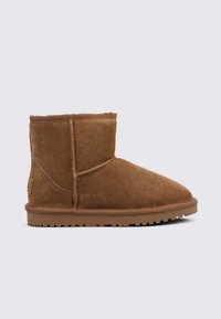 Bottine en suede marron avec un bout arrondi et un profil bas. Présente une surface texturée et une semelle en caoutchouc avec une bonne adhérence.