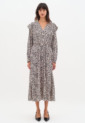 Leopardenmuster Wickelkleid mit langen Ärmeln, elastischem Bund und fließender Silhouette, aus leichtem Stoff gefertigt. Schwarze Akzent-Schuhe.