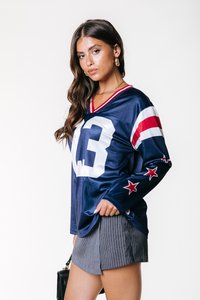 Marine fotballdrakt med stort hvitt nummer "13", røde og hvite stripete ermer, og stjerneakenter på ermene, parret med grå stripete shorts.