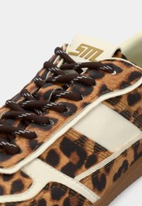 Baskets à imprimé léopard marron avec des accents crème et des lacets marron. Dispose d'une étiquette logo proéminente sur la languette et d'une semelle extérieure en caoutchouc texturée.