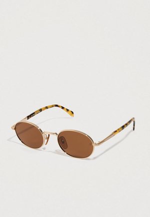 Round brown-lensed sunglasses with thin gold metal frames and tortoiseshell-patterned arms resting on a light surface.