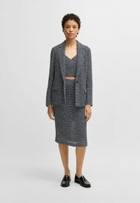 Navy and white textured knit two-piece outfit with a cropped top and fitted skirt, paired with black loafers and a loose blazer.