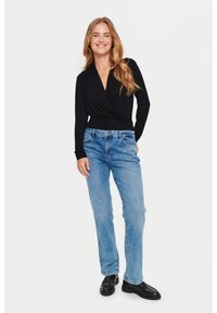 Mustapaita, jossa pitkät hihat ja kietaisumalli, yhdistettynä vaaleansinihin suoriin farkkuihin ja mustiin loafer-kengiin. Silkkinen kangas ja klassinen denim-textuuri.