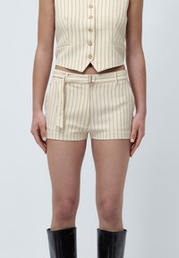 Beige stripete crop vest og shorts-sett, med en tettsittende design, funksjonelle lommer og et knyttet belte for et skreddersydd utseende.