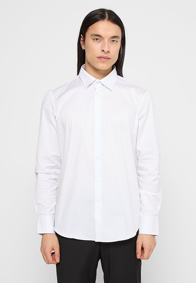 Chemise blanche à manches longues avec un col standard, en tissu lisse, présentant une patte de boutonnage à l'avant et un design ajusté.