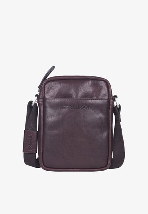 Petit sac à bandoulière en cuir marron foncé avec bandoulière noire réglable et fermeture éclair en haut, avec nom de marque subtilement embossé à l’avant.