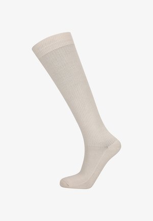 Chaussette beige jusqu'au genou avec une texture côtelée s'étendant de l'orteil jusqu'au bord, présentée sur une forme en pied sur fond blanc.