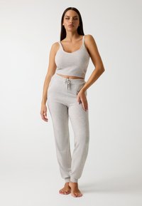 Világosszürke, bordázott, crop top, pántos pántokkal és hozzáillő, húzózsinóros joggersnadrággal; puha anyagú és laza szabású. Nincsenek minták vagy fém részletek.