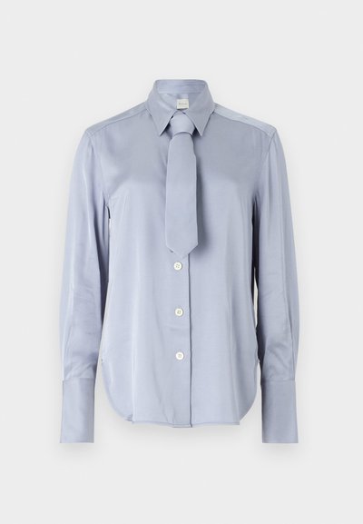 Světle modrá košile s dlouhým rukávem z hladké látky má klasický límeček a odpovídající kravatu. Má zapínání na knoflíky vpředu a na manžetách.