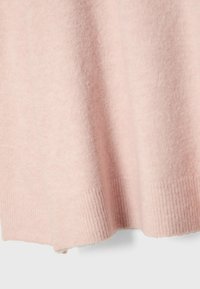 Tissu tricoté rose doux avec ourlet côtelé, montrant la texture et la chute d'un vêtement en laine ou cachemire.