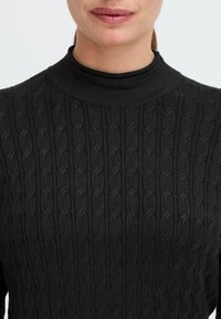 Schwarzer gestrickter Pullover mit hohem Kragen, einem strukturierten Zopfmuster, glattem Stoff und einer eng anliegenden Silhouette.