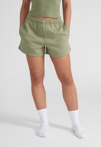 Lichtgroene katoenen shorts met een elastische tailleband en zijzakken, met een gebogen zoom. Draag voorzien van witte geribde enkelsokken.