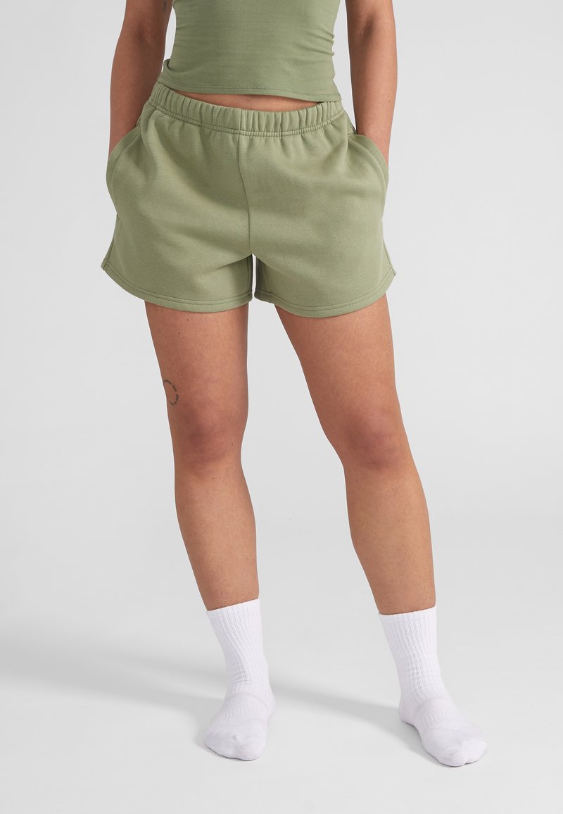 Lichtgroene katoenen shorts met een elastische tailleband en zijzakken, met een gebogen zoom. Draag voorzien van witte geribde enkelsokken.