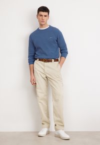 Blauwe textuur trui, beige broek, bruin riem en witte sneakers. Casual outfit met een comfortabele pasvorm. Eenvoudig ontwerp en neutrale kleuren.