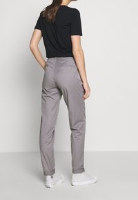 Grå bomullsshorts med avslappnad passform, uppvikta ärmar och bakfickor. Parat med en svart t-shirt med kort ärm och vita sneakers.