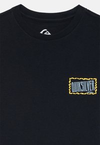 Svart bomulls T-skjorte med rund hals, med en liten, rektangulær gul og blå logo på venstre brystområde. Jevn tekstur.