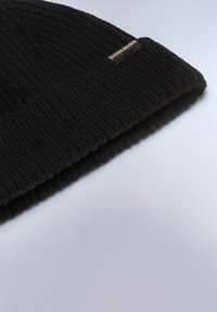 Beanie nero a maglia con un motivo testurizzato, dotato di risvolto e di un piccolo tag con il marchio sul lato.