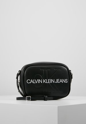 Sort crossbody taske lavet af glat syntetisk materiale. Har præget logo og justerbar rem. Minimalistisk design med lynlåslukning.