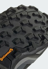 Semelle extérieure en caoutchouc noir avec un motif de traction multidirectionnel. Dotée d'une surface texturée et d'un logo Continental en orange.