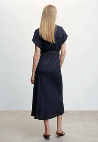 Laivan sininen, raidallinen mekko lyhyillä hihoilla, vyötäröllä vyö ja lentävä A-linjainen hame. Silkkinen kangas, jossa on hienoinen kiilto.