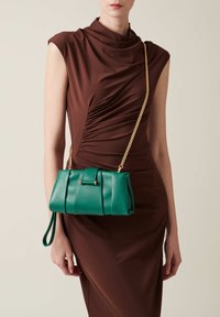 Grüne Lederhandtasche mit strukturierter Form, ausgestattet mit Raffung und einem goldenen Kettenriemen. Die Tasche hat einen frontalen Deckel und einen Handgelenkriemen.