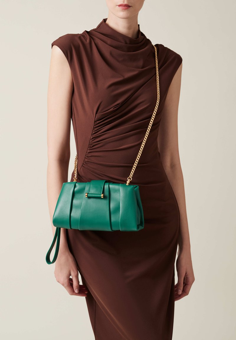 Grüne Lederhandtasche mit strukturierter Form, ausgestattet mit Raffung und einem goldenen Kettenriemen. Die Tasche hat einen frontalen Deckel und einen Handgelenkriemen.