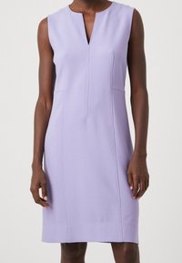 Sukienka bez rękawów w jasnolawendowym kolorze z dekoltem w kształcie litery V i szczegółami przeszyć z przodu. Charakteryzuje się dopasowaną sylwetką i długością do kolan.