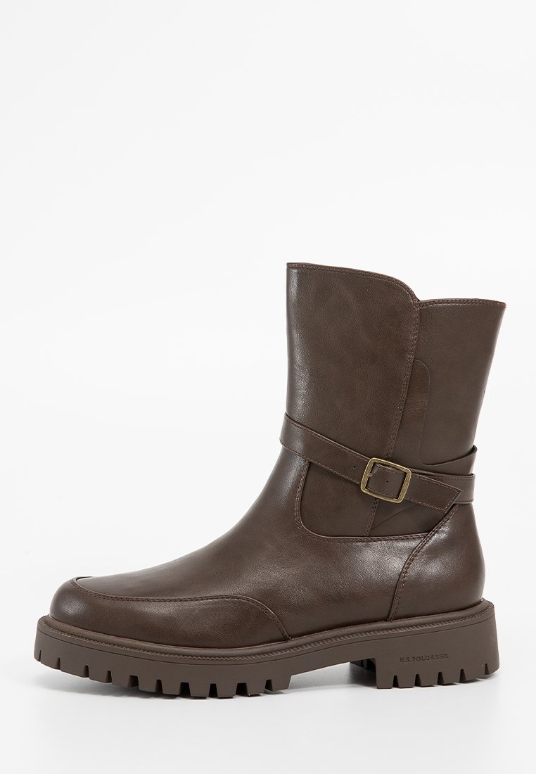 Bottillon en cuir marron avec un large revers, sangle latérale et détail de boucle, semelle robuste et couture simpliste sur le capuchon.