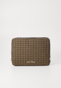 Kocúk na laptop s kockovaným vzorom v houndstooth v hnedej, krémovej a čiernej farbe. Texturovaná tkanina so strieborným zipsom a detailom loga.