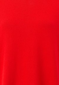 Tissu en maille rouge avec une texture lisse, présentant un motif de tissage uniforme sur toute la surface. Aucune quincaillerie visible ni accents supplémentaires.