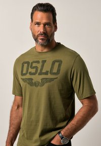 Tyrkysové bavlněné tričko s výrazným potiskem "OSLO" a grafikou křídel. Krátké rukávy, kulatý výstřih, hladký povrch a ležérní střih.