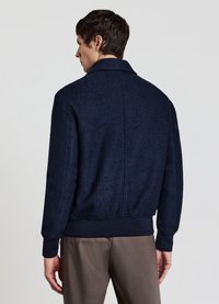 Giacca in misto lana blu navy con colletto a punta, polsini e orlo a costine, finitura testurizzata e cuciture pulite sul retro.