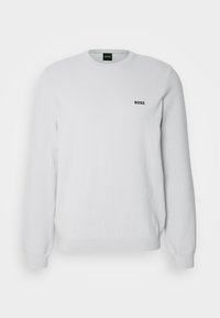 Pull blanc à manches longues col rond avec poignets côtelés, tissu subtilement texturé, et petit logo noir "BOSS" sur la poitrine gauche.