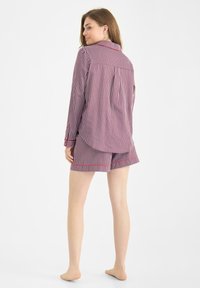 Set di pigiama a righe in rosso e bianco, composto da una camicia con bottoni e colletto e pantaloni corti abbinati. Tessuto morbido con una vestibilità comoda.