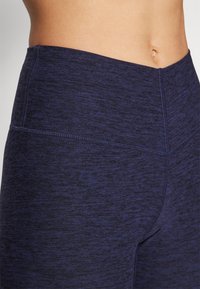 Marineblå high-waisted leggings med en teksturert, melert finish. Har sømløs midje og sømdetaljer for et slankt utseende.