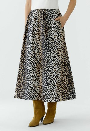 Maxi-Rock mit Leopardenmuster aus leichtem Stoff, mit elastischem Bund und seitlichen Taschen, kombiniert mit knielangen, hellbraunen Wildlederstiefeln.