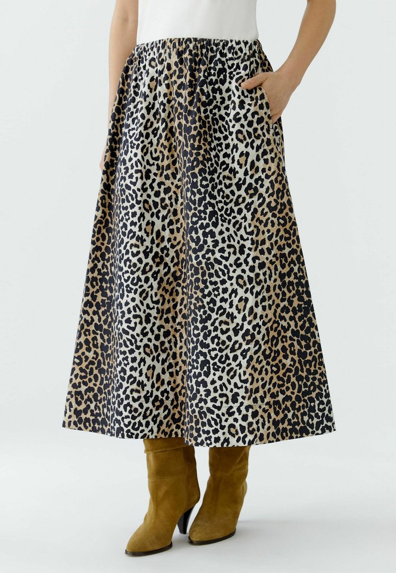 Maxi-Rock mit Leopardenmuster aus leichtem Stoff, mit elastischem Bund und seitlichen Taschen, kombiniert mit knielangen, hellbraunen Wildlederstiefeln.