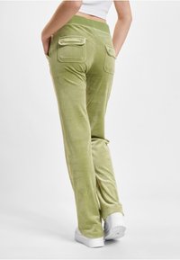 Zielone welurowe spodnie o luźnym kroju, z dwiema tylnymi kieszeniami i miękką fakturą. Połączone z białymi trampkami i dopasowaną bluzką.