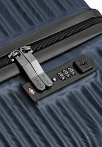 Candado de combinación de la TSA en maleta de texturizado azul oscuro con dos tiradores de cremallera metálicos etiquetados "REDOLZ."