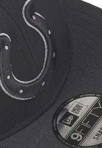 Casquette noire avec un motif en gris brodé proéminent ressemblant à un "S" stylisé. Comprend une étiquette de taille New Era circulaire sur le côté.