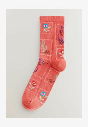 Calcetines coral con un patrón completo que presenta flores, cactus y sombreros en colores brillantes, tejido texturizado y detalle en la puntera de color contrastante.